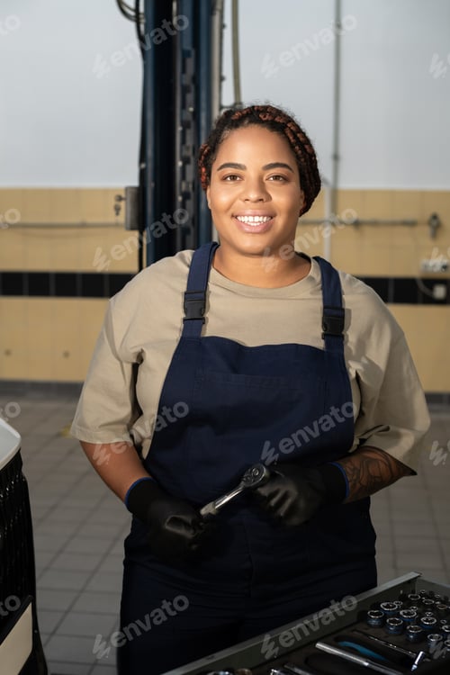 Preview: Empowered female mechanic proudly working on a vehicle in a bustling auto repair shop