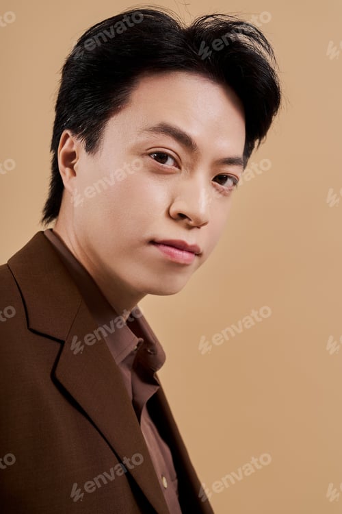 Preview: Stylish young man exudes elegance in brown blazer during studio session