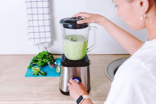 Preview: Woman is making homemade healthy smoothie. Vegetarian green cocktail from spinach