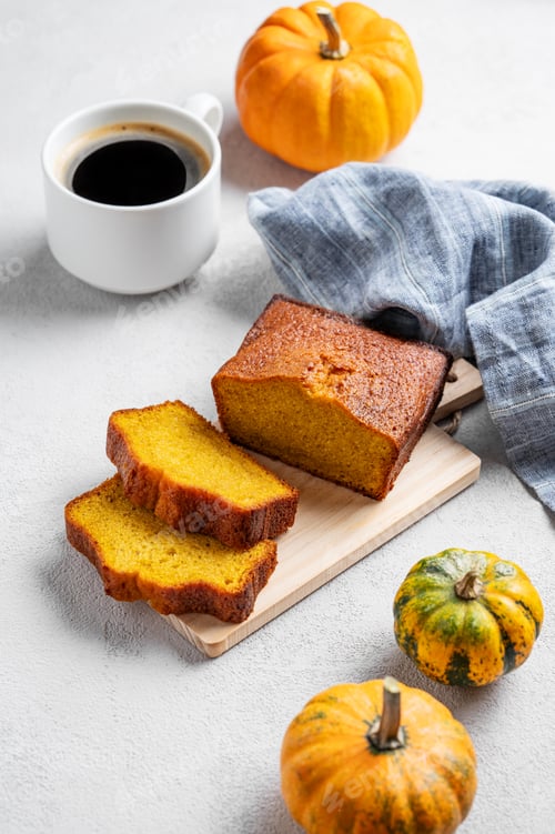 Preview: Pumpkin sweet bread on a wooden board on a light background with decorative pumpkins