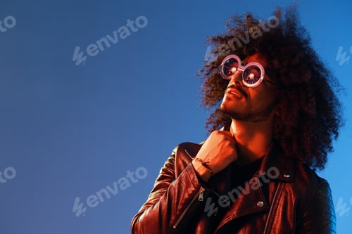 Preview: Portrait of a stylish man with curly hair with glasses smile on blue background multinational, color