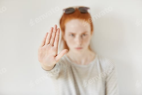 Preview: Young annoyed woman with bad attitude making stop gesture with her palm outward, saying no, expressi
