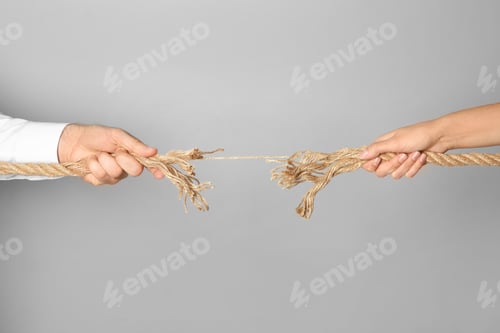 Preview: Man and woman pulling frayed rope at breaking point on gray background