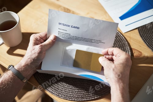 Preview: Senior Man Opening Envelope Holding Credit Card