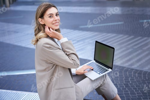 Preview: Young digital nomad, businesswoman sitting with laptop in city centre. Office worker using computer