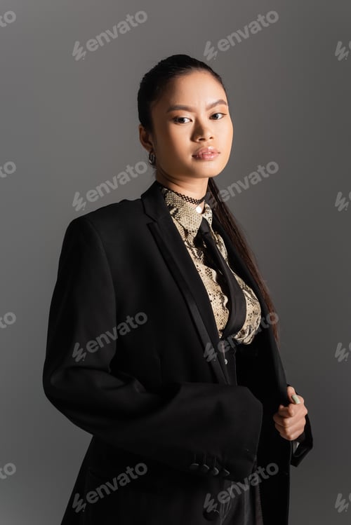 Preview: Portrait of asian model in black jacket looking at camera isolated on grey