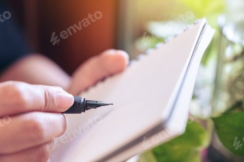 Preview: A woman holding and writing on notebook by fountain pen