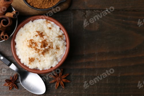 Preview: Tasty rice pudding with cinnamon served on wooden table, flat lay. Space for text