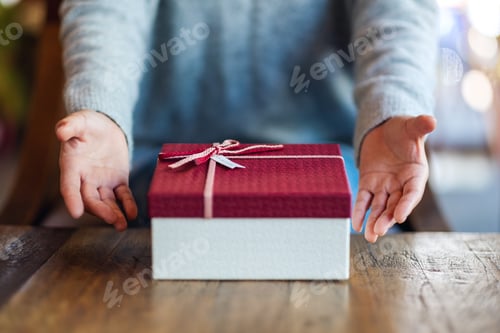 Preview: Closeup image of a woman giving and showing a red gift box