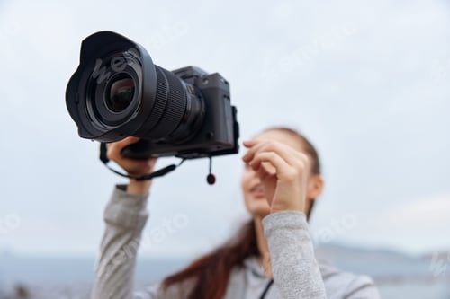 Preview: Young woman with a camera smiles outdoors, capturing moments, showcasing enthusiasm for photography