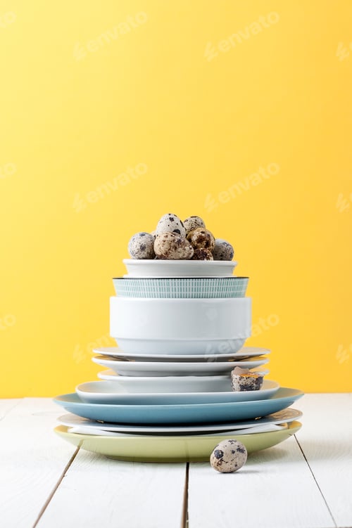 Preview: A stack of different tableware and quail eggs on a white wooden