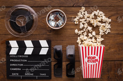 Preview: Clapperboard, film reel and popcorn on wooden background, top view