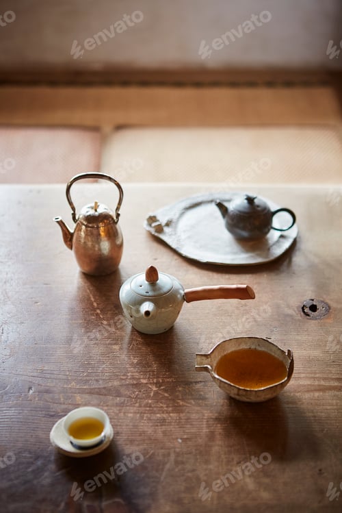 Preview: A serene tea setting with traditional teapots and cup on a wooden table.