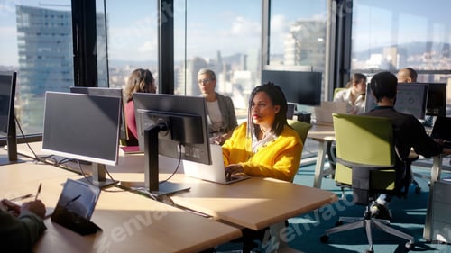 Preview: African woman working on laptop in modern office with colleagues