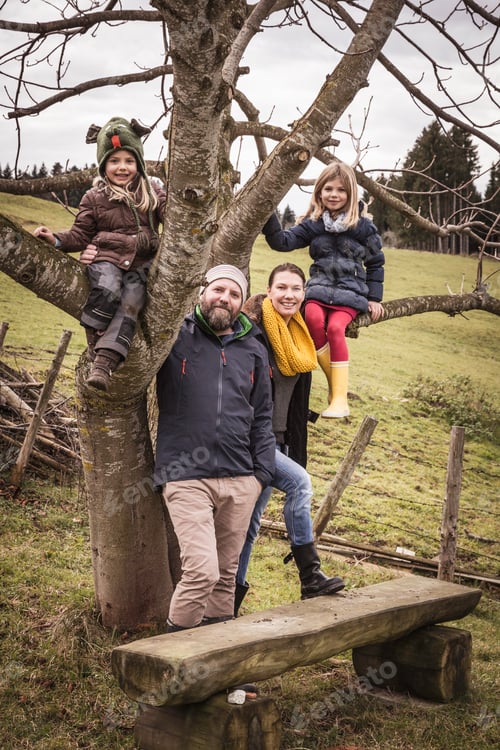 Preview: Portrait of couple with two daughters climbing bare tree