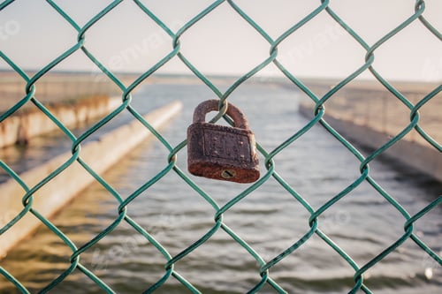 Preview: Rusted lock on turquoise wire fence at the beach