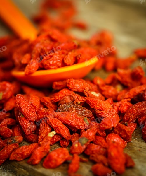 Preview: Goji Berries in a spoon on a wooden board.