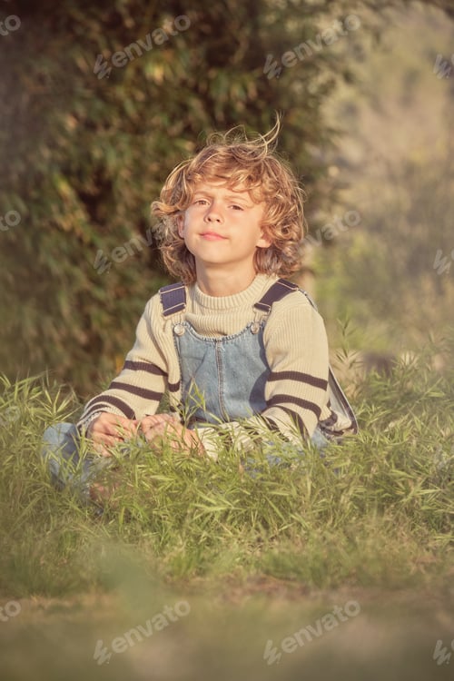 Preview: Boy sitting on grass on sunny day