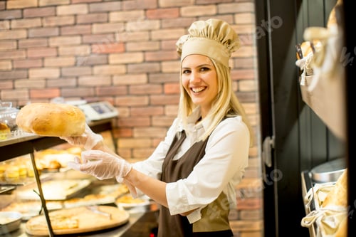 Preview: Young woman takes fresh bread from the shelves in a baker shop