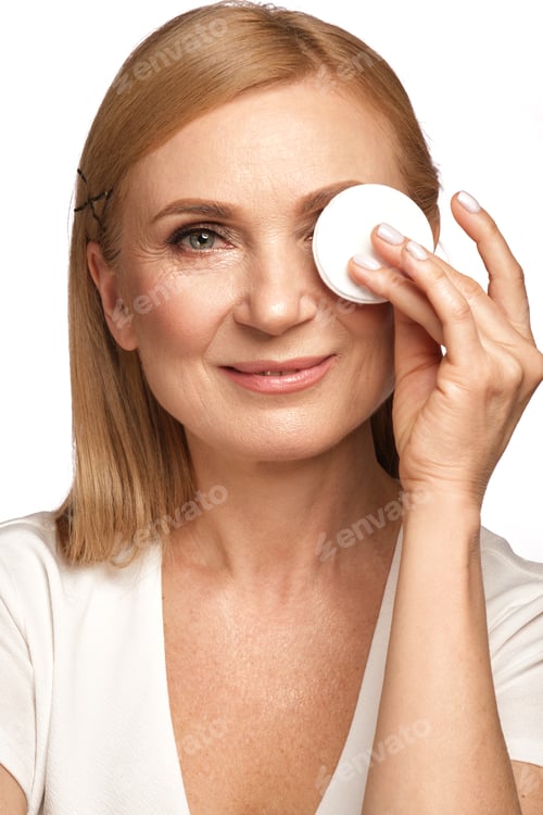 Vista previa: Retrato de una bella anciana quitándose el maquillaje con un limpiador y una almohadilla de algodón.