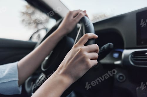 Preview: car interior showing a person driving with one hand on the steering wheel while the other adjusts