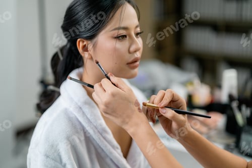 Preview: Makeup artist applying foundation on model face with cosmetic brush