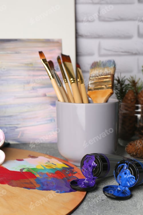 Preview: Artist's palette, tubes of colorful paints and brushes on textured table