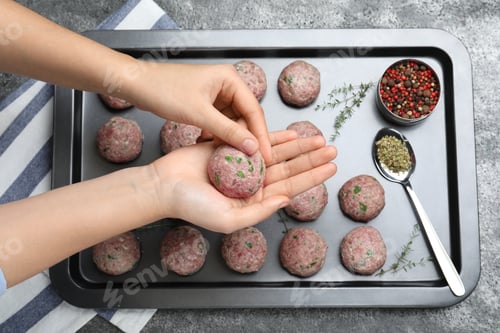 Preview: Woman making fresh raw meatballs at grey table, top view