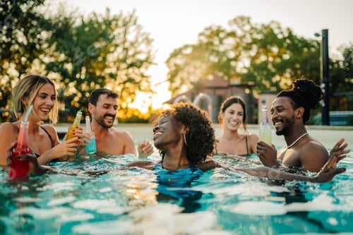 Preview: Friends enjoying drinks in swimming pool at sunset