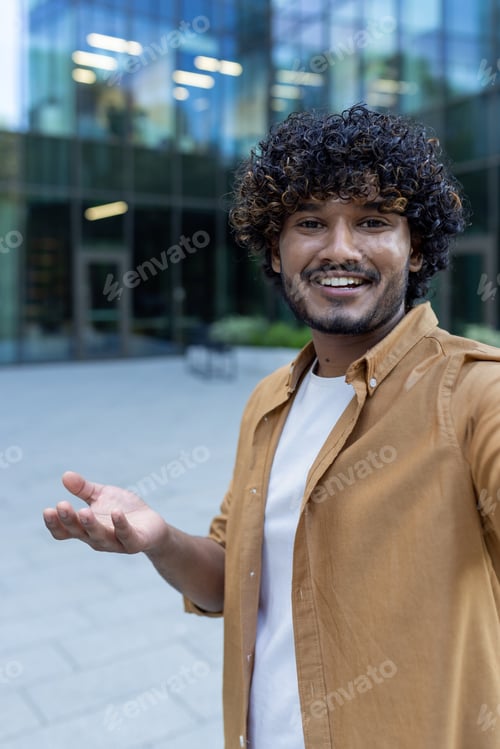 Preview: Close-up photo. Portrait of a young hispanic man filming a blog, recording a podcast outside. He