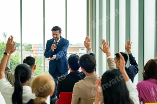 Preview: Raised up hands of large group in seminar class room to agree with speaker at conference seminar