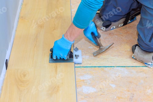 Preview: Skilled worker installing laminate flooring using tools in a home renovation project