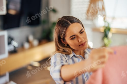 Preview: Woman Examining Pink Sweater Indoors During the Day