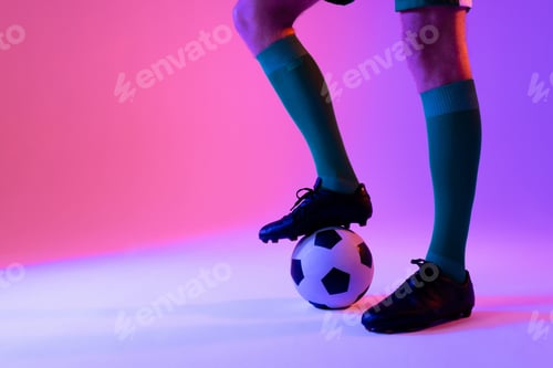 Preview: Caucasian male soccer player with football over neon pink lighting