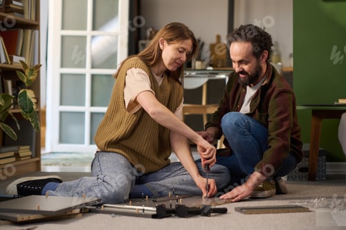 Preview: Young Woman and Middle Aged Man Assembling Furniture Together Indoors