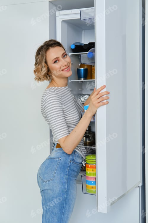 Preview: Portrait of a woman taking out the fridge breakfast products