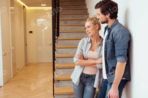 Aperçu: smiling couple standing near stairs at home