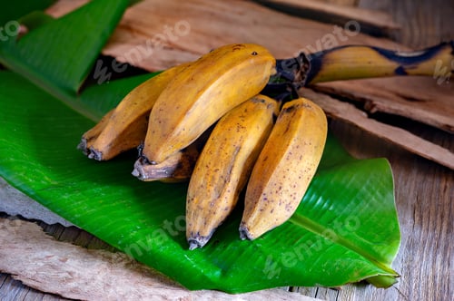 Preview: Bunch of ripe bananas resting on vibrant green banana leaf