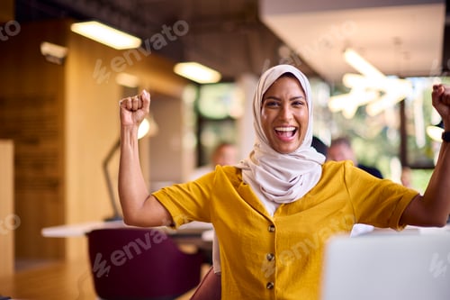 Preview: Portrait Of Excited Mature Businesswoman Wearing Headscarf Celebrating Working At Desk In Office
