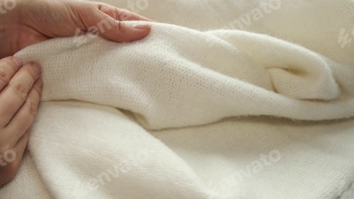 Preview: female's hand on the fabric of white plush cloth with soft nap. Clothing industry concept, slow