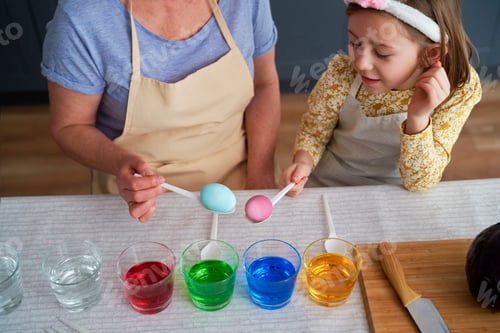 Preview: Top view of granddaughter and grandmother dyeing Easter eggs together
