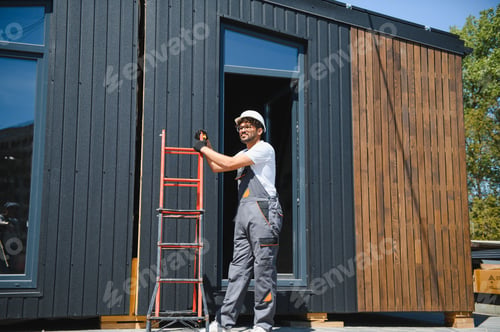 Preview: Construction worker holding ladder near modular house
