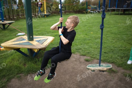 Preview: the boy goes through an obstacle course is engaged in active sports sits on a suspended swing