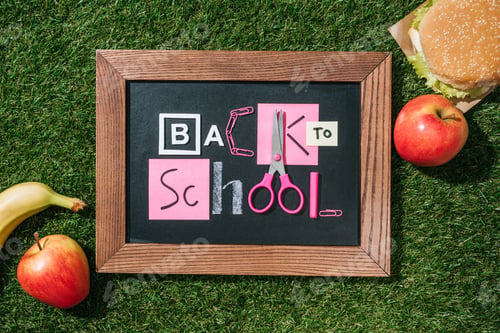 Preview: flat lay with fresh apples, banana, burger and blackboard with back to school lettering made of pink