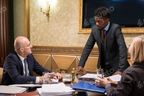 Preview: Mature man and woman looking at their young African male colleague