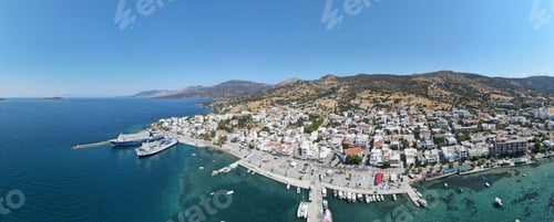 Preview: Wide-angle shot of the Marmari coast harbor during daytime with a clear blue sky, Greece