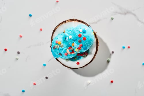Preview: top view of delicious blue ice cream with sprinkles on coconut half on marble grey background