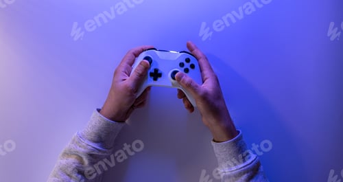 Preview: Male hands hold a gamepad on a blue background, copy space.