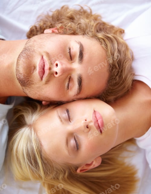 Preview: Rest and relaxation. A young couple sleeping in bed with their heads together.