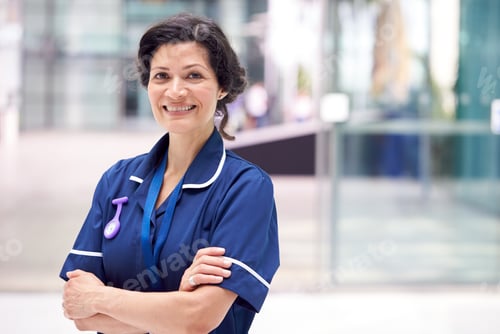 Preview: Portrait Of Mature Female Nurse Wearing Uniform Standing In Modern Hospital Building